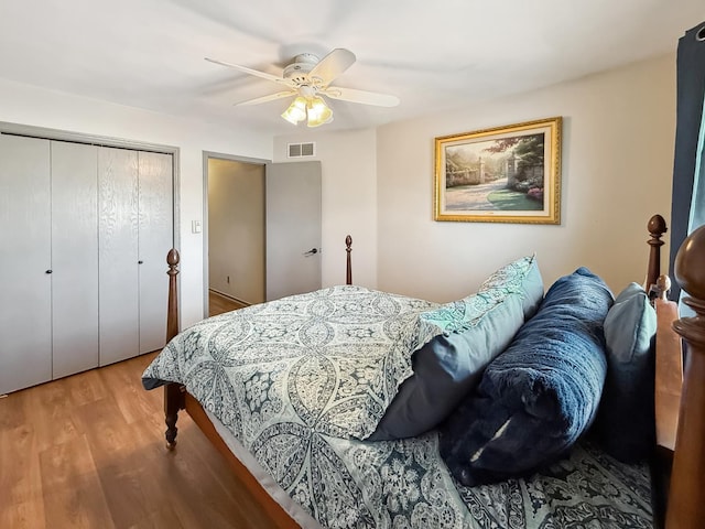 bedroom featuring a ceiling fan, a closet, visible vents, and wood finished floors