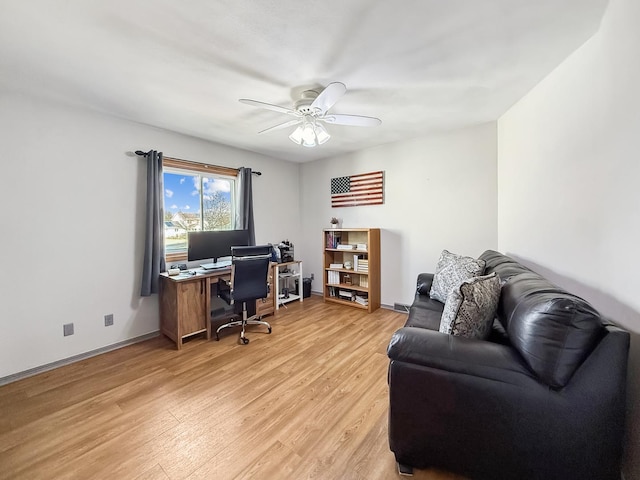 office space with light wood-type flooring, ceiling fan, and baseboards