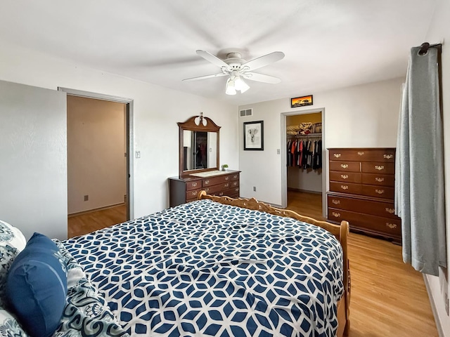 bedroom with light wood finished floors, visible vents, ceiling fan, a spacious closet, and a closet