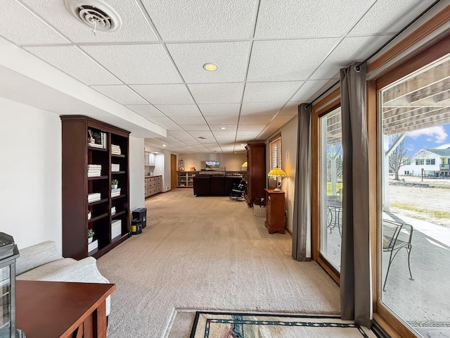 interior space with light carpet, a paneled ceiling, and visible vents