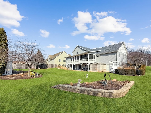 rear view of property with a sunroom, fence, and a lawn