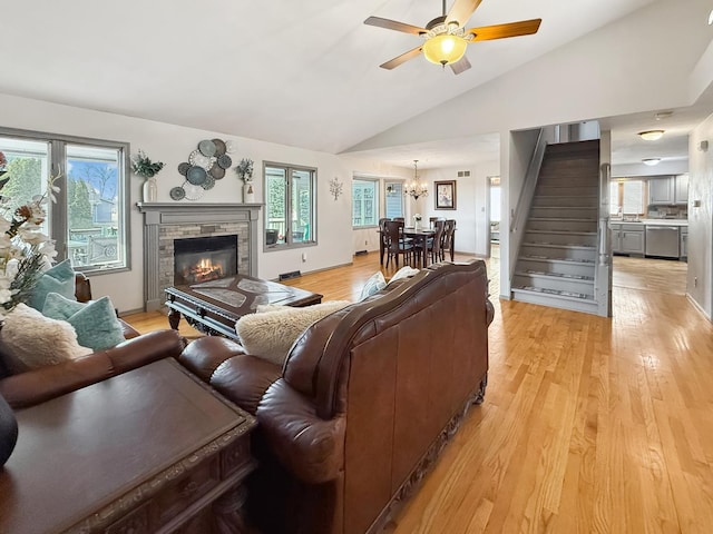 living room with stairway, vaulted ceiling, plenty of natural light, and light wood-style flooring