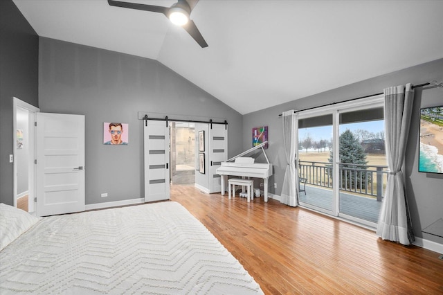 bedroom with baseboards, wood finished floors, a barn door, and access to outside