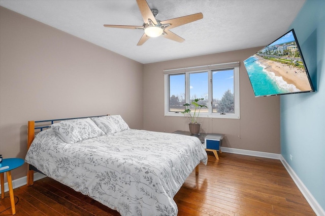 bedroom with hardwood / wood-style floors, ceiling fan, baseboards, and a textured ceiling