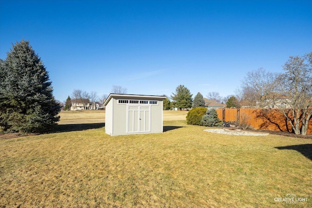 view of yard featuring a storage shed, fence, and an outdoor structure