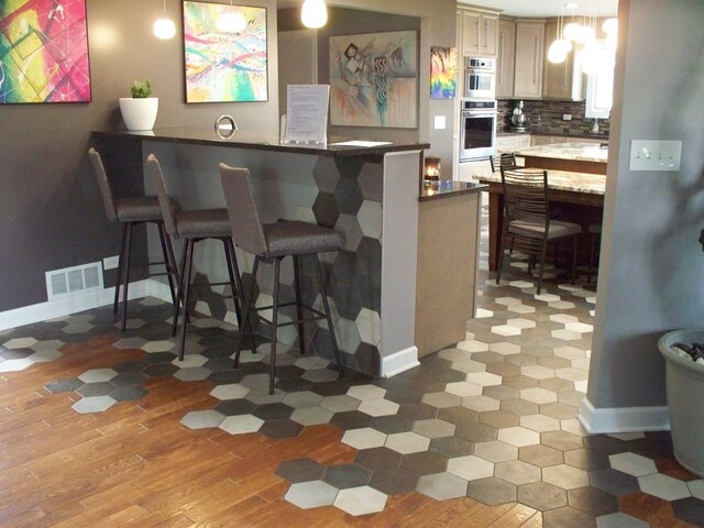 kitchen with visible vents, baseboards, recessed lighting, a peninsula, and a kitchen breakfast bar