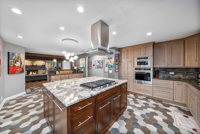 kitchen featuring island range hood, a center island, decorative backsplash, appliances with stainless steel finishes, and a large fireplace