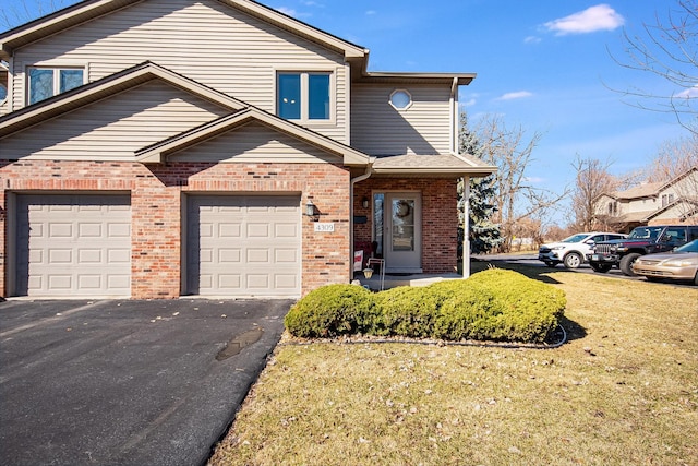 view of property with a garage, brick siding, driveway, and a front lawn