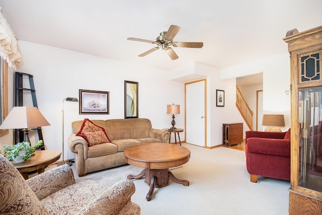 carpeted living room with ceiling fan, stairs, and baseboards