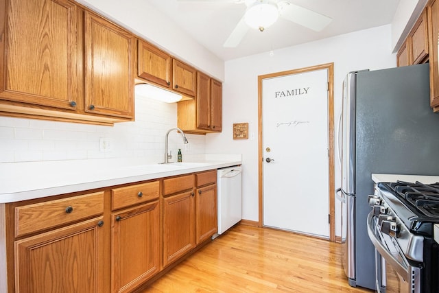 kitchen with light wood finished floors, decorative backsplash, dishwasher, brown cabinets, and a sink