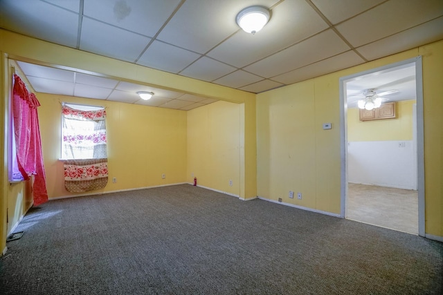 carpeted spare room featuring a drop ceiling and baseboards