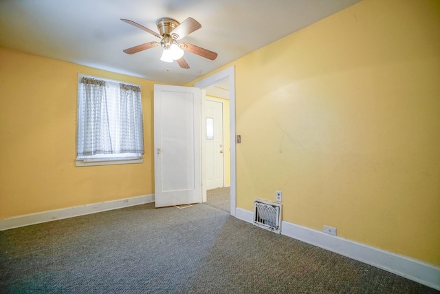 carpeted empty room featuring a ceiling fan, visible vents, and baseboards