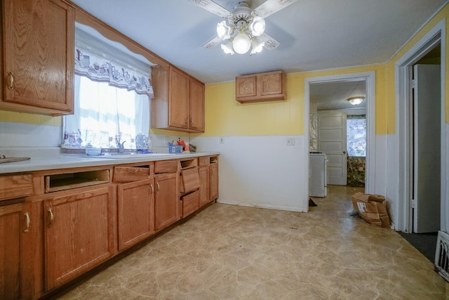 kitchen featuring brown cabinetry, light countertops, a ceiling fan, and a sink