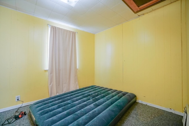 bedroom with baseboards, carpet, and wooden walls