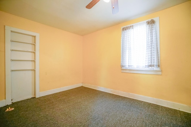 spare room with built in features, baseboards, a ceiling fan, and dark carpet