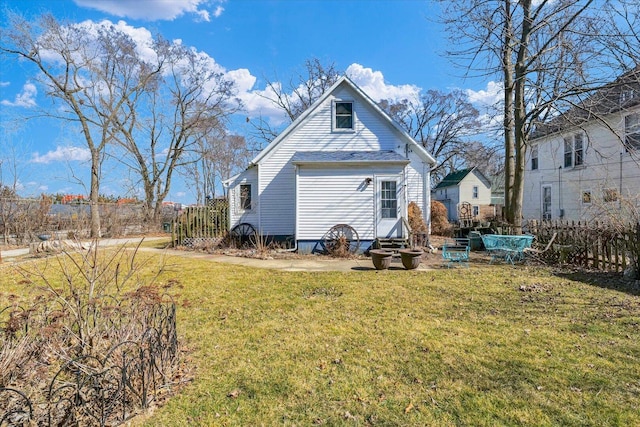 rear view of property featuring a yard and fence