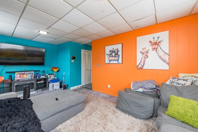 living area featuring carpet, a drop ceiling, and baseboards