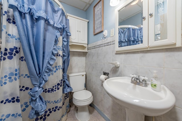 bathroom featuring toilet, a shower with curtain, tile walls, and a sink