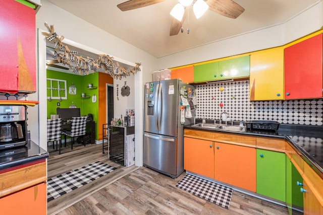 kitchen featuring beverage cooler, a sink, light wood finished floors, dark countertops, and stainless steel fridge