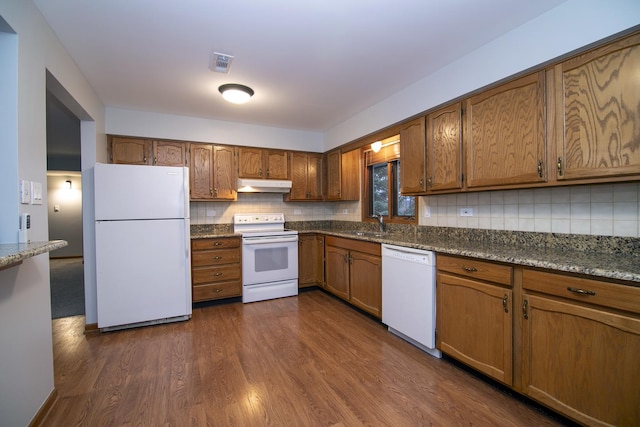 kitchen with visible vents, brown cabinetry, dark wood-type flooring, white appliances, and under cabinet range hood