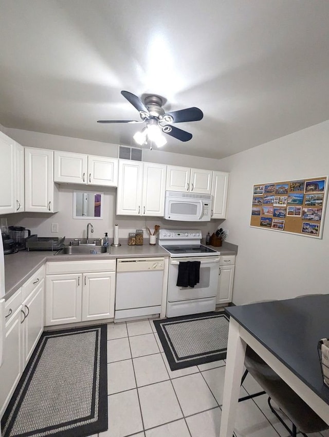 kitchen featuring white appliances, white cabinetry, a sink, and light tile patterned floors