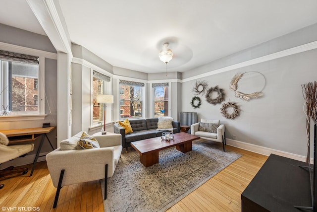 living area featuring a ceiling fan, baseboards, and wood-type flooring