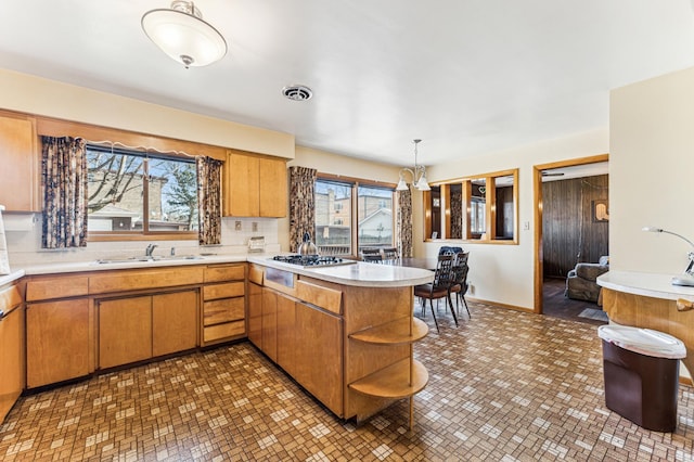 kitchen featuring a peninsula, gas stovetop, visible vents, light countertops, and open shelves