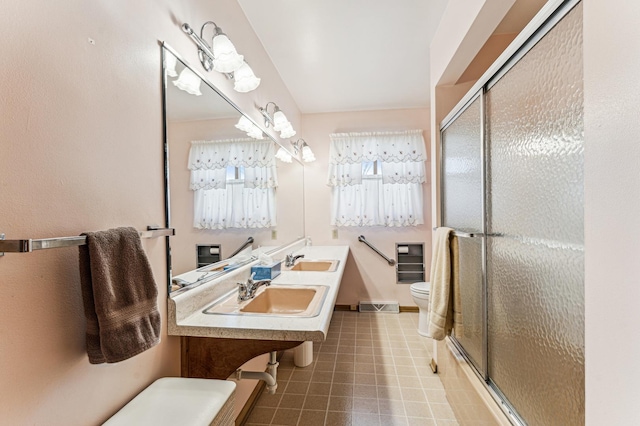 full bath featuring a shower with door, visible vents, toilet, double sink, and tile patterned floors