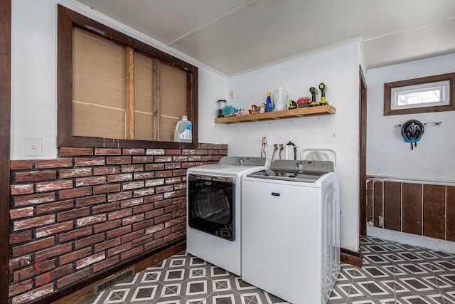 washroom featuring laundry area, washing machine and dryer, brick wall, and visible vents
