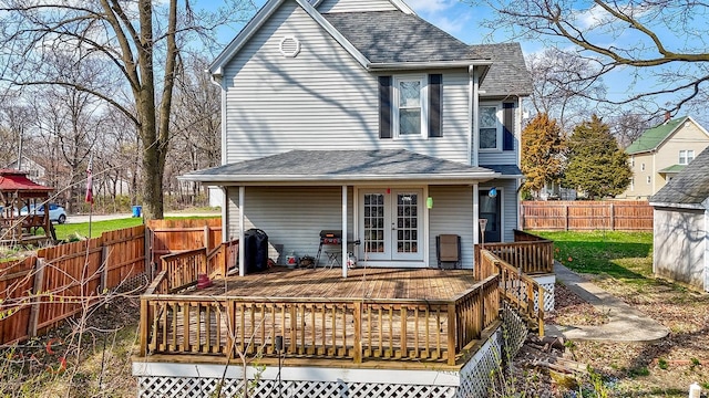 rear view of property featuring french doors, a wooden deck, a shingled roof, and a fenced backyard