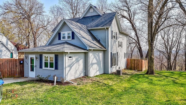 rear view of property featuring a lawn, roof with shingles, and fence