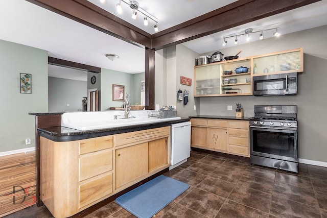 kitchen featuring light brown cabinets, dark countertops, baseboards, a sink, and appliances with stainless steel finishes