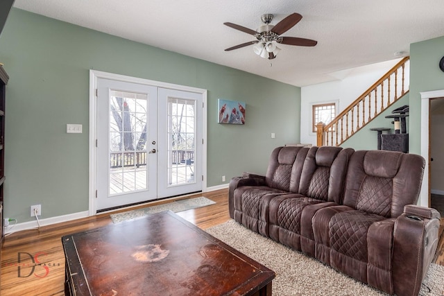 living area with ceiling fan, french doors, stairs, baseboards, and wood finished floors