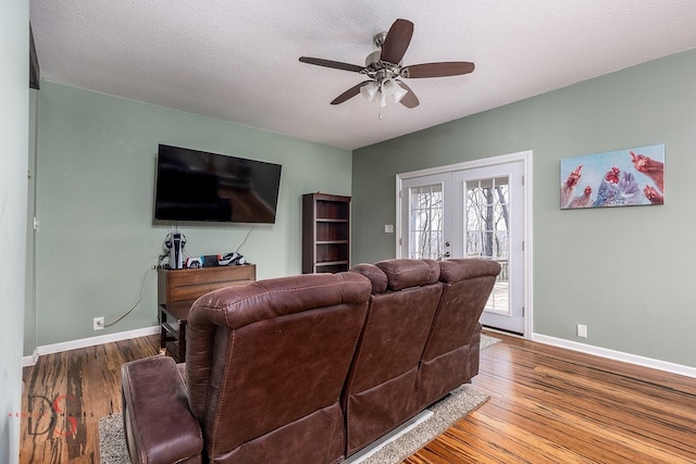 living room with wood finished floors, baseboards, ceiling fan, a textured ceiling, and french doors