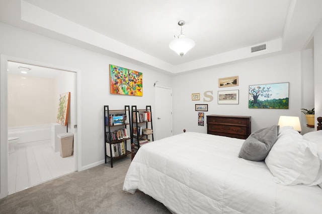 bedroom with light carpet, visible vents, and a tray ceiling