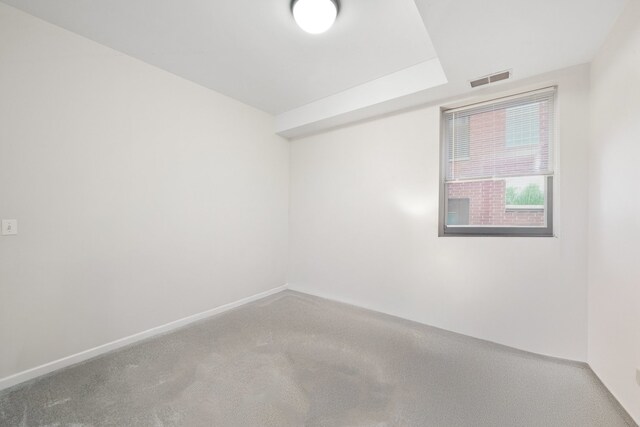 carpeted spare room featuring visible vents and baseboards