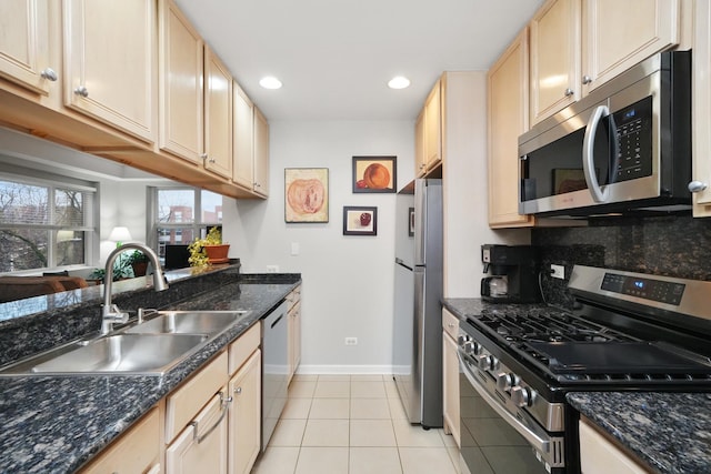 kitchen with light tile patterned floors, baseboards, decorative backsplash, stainless steel appliances, and a sink