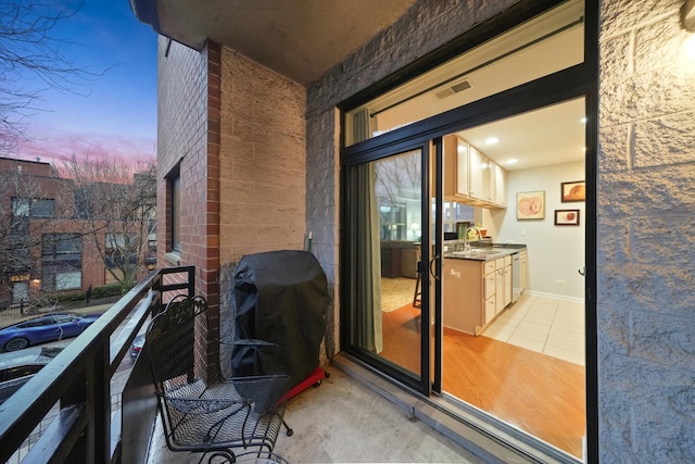 balcony at dusk with area for grilling, a sink, and visible vents