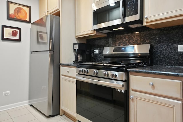 kitchen with appliances with stainless steel finishes, cream cabinetry, light tile patterned flooring, and tasteful backsplash