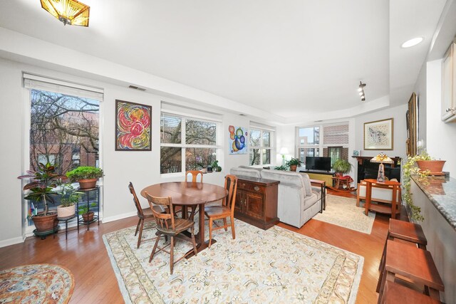 dining room featuring visible vents, baseboards, light wood-style flooring, a tray ceiling, and recessed lighting