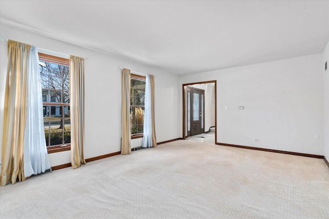 spare room with light colored carpet and baseboards