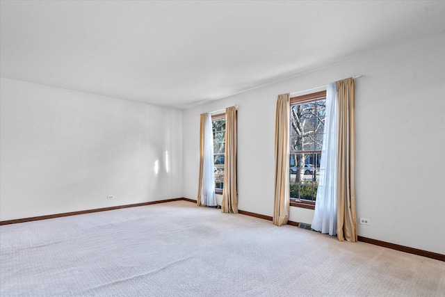 empty room featuring baseboards and light carpet