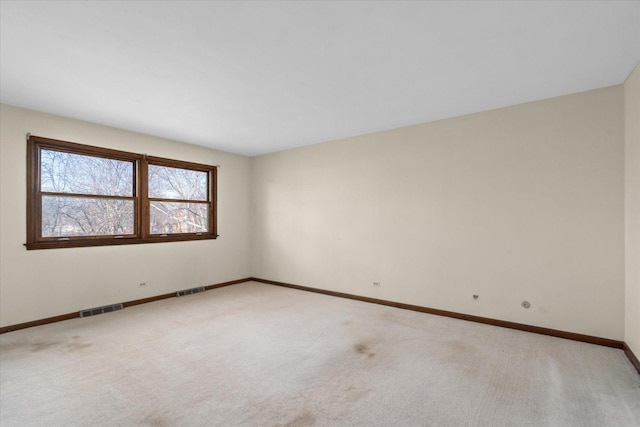 empty room featuring visible vents, light carpet, and baseboards