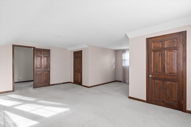 unfurnished room featuring light carpet, baseboards, and vaulted ceiling