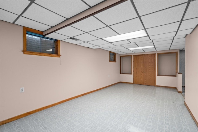 finished basement with visible vents, a paneled ceiling, baseboards, and light floors