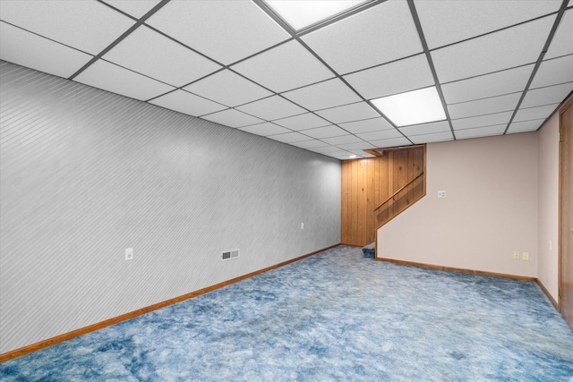 finished basement featuring carpet flooring, baseboards, visible vents, and a drop ceiling