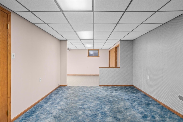 finished below grade area featuring carpet, a paneled ceiling, and baseboards