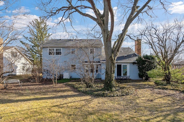 rear view of property featuring a chimney and a yard