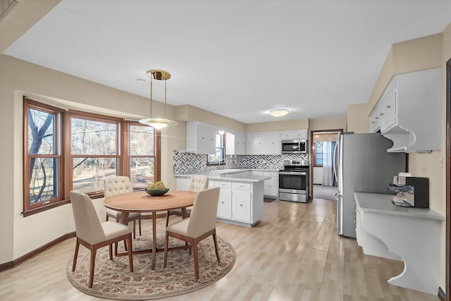 dining area with light wood finished floors, a healthy amount of sunlight, and baseboards