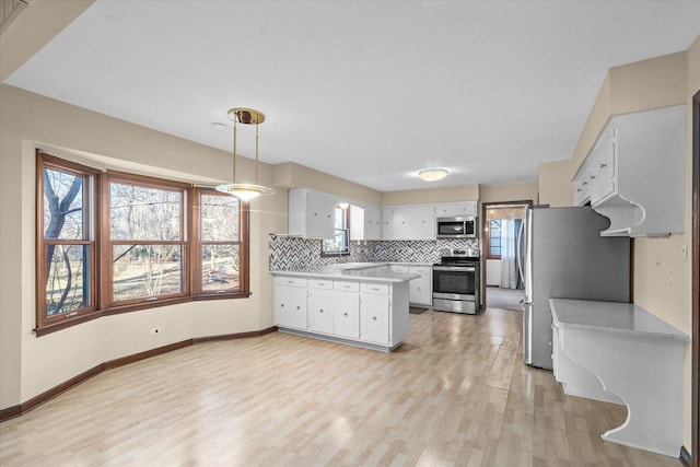 kitchen with light countertops, decorative backsplash, light wood-style flooring, stainless steel appliances, and white cabinetry